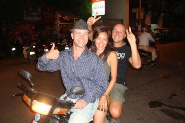 Ramon Stoppelenburg driving a moto with two passengers in Cambodia