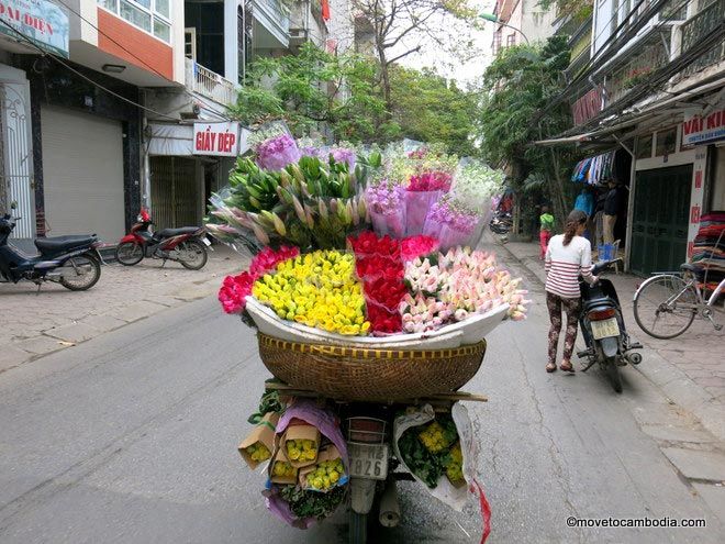 A motobike with a giant basket of flowers on the back in Hanoi.